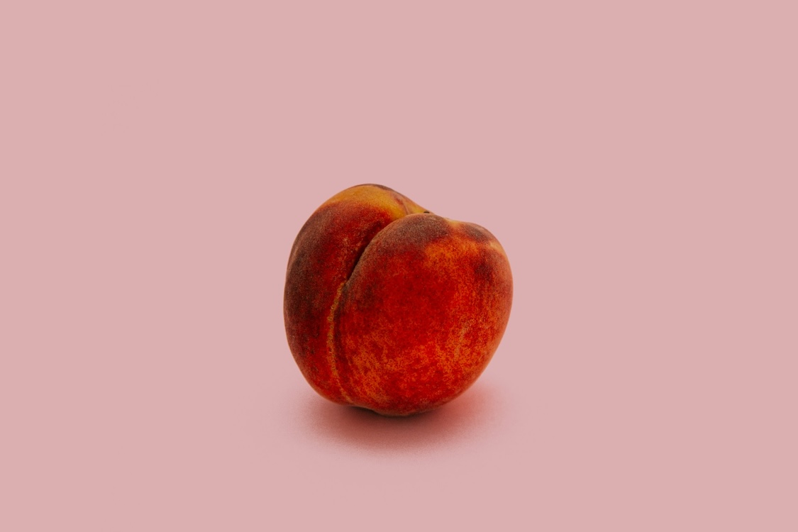 A peach on a purple background, symbolising the peaches of UX design - Unsplash